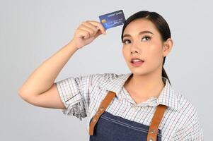 retrato de jovem asiática em uniforme de garçonete pose com cartão de crédito foto
