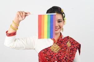 retrato do jovem mulher dentro tailandês nordeste tradicional roupas segurando arco Iris bandeira foto