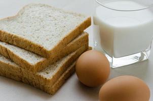 fatiado todo trigo pão, fervido ovo e leite para café da manhã foto