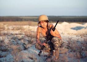 jovem fêmea soldado vestido dentro uma camuflar com uma arma de fogo dentro a ao ar livre foto