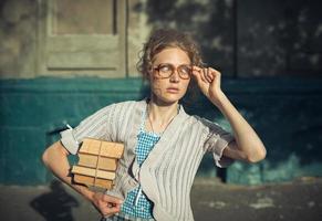 engraçado menina aluna com livros dentro óculos e uma vintage vestir foto