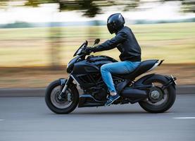 jovem homem equitação uma esporte motocicleta em a estrada foto