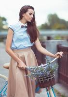 jovem bonita e elegantemente vestida com bicicleta foto