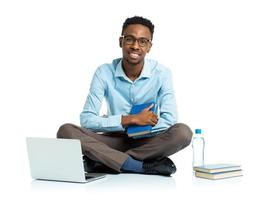 feliz africano americano Faculdade aluna sentado com computador portátil em branco fundo foto