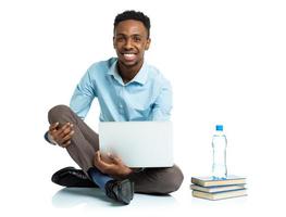 feliz africano americano Faculdade aluna sentado com computador portátil em branco fundo foto