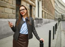 empresária caminhando baixa a rua enquanto falando em inteligente telefone foto