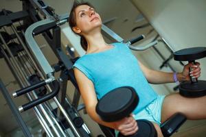 mulher com halteres dentro a Academia fazendo exercícios foto