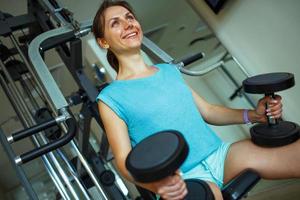 mulher com halteres dentro a Academia fazendo esporte exercícios foto