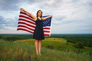 orgulhoso mulher com uma nos bandeira é em pé em topo do uma Colina foto