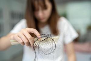 mulher asiática tem problema com perda de cabelo comprido anexar a escova de pente. foto