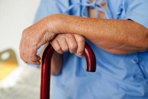 ásia idosos incapacidade mulher paciente segurando caminhando bastão dentro enrugado mão às hospital. foto