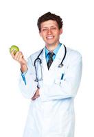retrato do uma sorridente masculino médico segurando verde maçã em branco foto