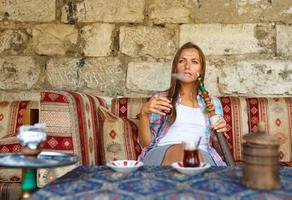 mulher fumar uma narguilé e bebendo chá dentro uma cafeteria, Istambul, Peru foto
