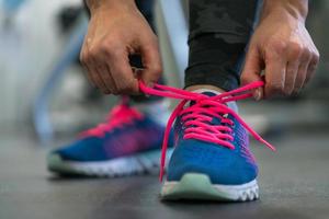 corrida sapatos - mulher amarrar sapato laços. mulher obtendo pronto para se empenhar dentro a Academia foto