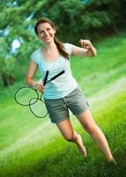 sorridente menina com uma raquete para uma badminton dentro a parque foto