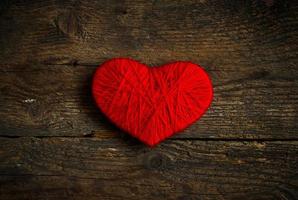 vermelho coração forma fez a partir de lã em velho gasto de madeira fundo foto