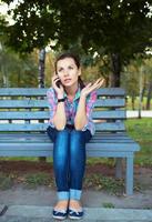 retrato do uma jovem mulher dentro uma parque falando em a telefone foto