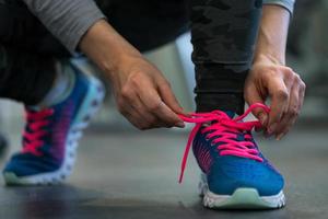 corrida sapatos - mulher amarrar sapato laços. mulher obtendo pronto para se empenhar dentro a Academia foto