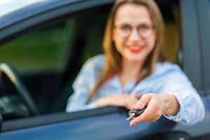 jovem bonita mulher sentado dentro uma carro com a chaves dentro mão foto