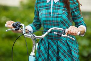 menina caminhando com dela bicicleta ao ar livre foto