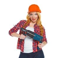 fêmea construção trabalhador dentro uma capacete com uma perfurador foto