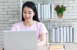 mulher asiática lendo e fazendo lição de casa foto