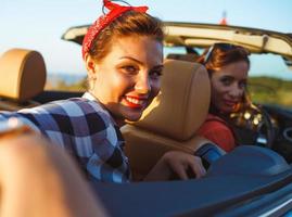 dois jovem meninas dirigindo uma cabriolet foto