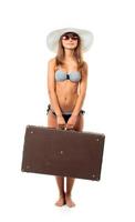 cheio comprimento retrato do uma lindo jovem mulher posando dentro uma bikini com uma mala de viagem dentro mão em branco foto