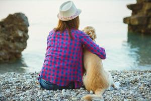 mulher com uma cachorro sentado em a de praia foto