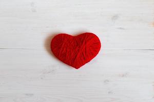 vermelho coração forma fez a partir de lã em branco de madeira fundo foto