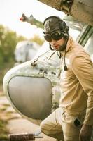 jovem piloto posando perto a helicóptero foto