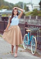 jovem lindo, elegantemente vestido mulher com bicicleta ao ar livre foto