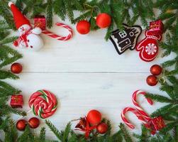 Natal fronteira com abeto árvore galhos, Natal decorações e doce bengala em branco de madeira Pranchas foto