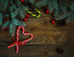 Natal fronteira com abeto árvore, cones, Natal decorações e doce bengala em de madeira Pranchas foto