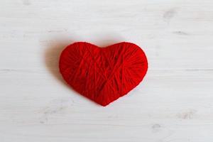 vermelho coração forma fez a partir de lã em branco de madeira fundo foto
