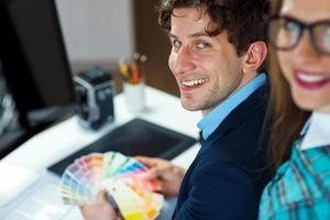 jovem colega olhando para uma cor pintura paleta às casa escritório foto