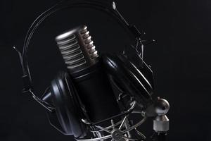 profissional microfone com Preto fones de ouvido sobre Preto fundo em branco mármore mesa foto