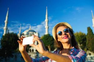 menina dentro a chapéu fazer selfie de a Smartphone em a fundo do a azul mesquita, Istambul foto