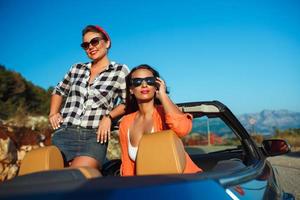 dois jovem meninas tendo Diversão dentro a cabriolet ao ar livre foto