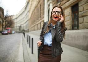 empresária caminhando baixa a rua enquanto falando em inteligente telefone foto