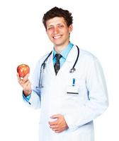 retrato do uma sorridente masculino médico segurando vermelho maçã em branco foto