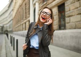 empresária caminhando baixa a rua enquanto falando em inteligente telefone foto