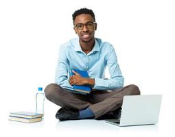 feliz africano americano Faculdade aluna com computador portátil, livros e garrafa do água sentado em branco foto