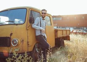 jovem bonito à moda homem, vestindo camisa e gravata-borboleta com velho carros foto