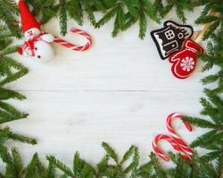 Natal fronteira com abeto árvore galhos, Natal decorações e doce bengala em branco de madeira Pranchas foto