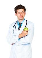 retrato do uma sorridente masculino médico segurando verde maçã em branco foto