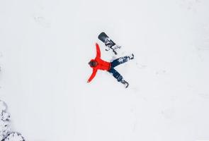 aéreo Visão do uma homem deitado dentro a neve Próximo para dele snowboard foto