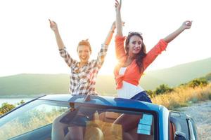 dois jovem feliz meninas tendo Diversão dentro a cabriolet ao ar livre foto