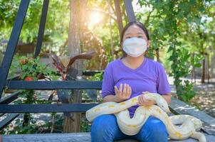 jovem menina vestem mascarar e aguarde a albino Pitão, animal foto