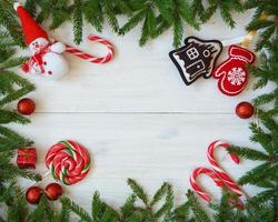 Natal fronteira com abeto árvore galhos, Natal decorações e doce bengala em branco de madeira Pranchas foto